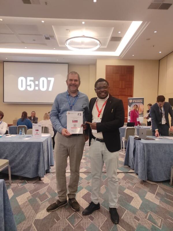Two men holding a meeting card in front of a countdown clock at the NET24 conference